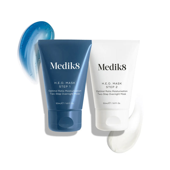 Produktbild av Medik8 H.E.O. Mask i två steg: en blå tub för steg 1 och en vit tub för steg 2, med konsistenser av båda krämerna i bakgrunden.-9