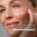 Närbild på en leende kvinna som applicerar Medik8 Liquid Peptides Advanced MP på kinden. Texten lyfter fram produktens bioteknologi, Dual MiniProteins™.
