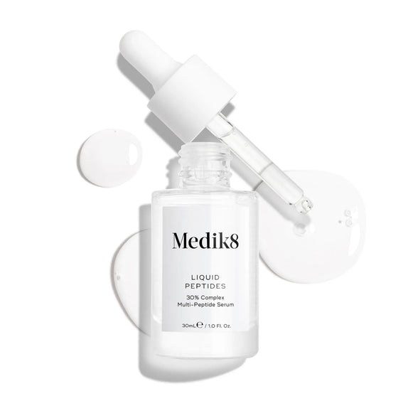 Produktbild av Medik8 Liquid Peptides, ett serum i en genomskinlig glasflaska med en pipett, tillsammans med vita droppar i bakgrunden.-12