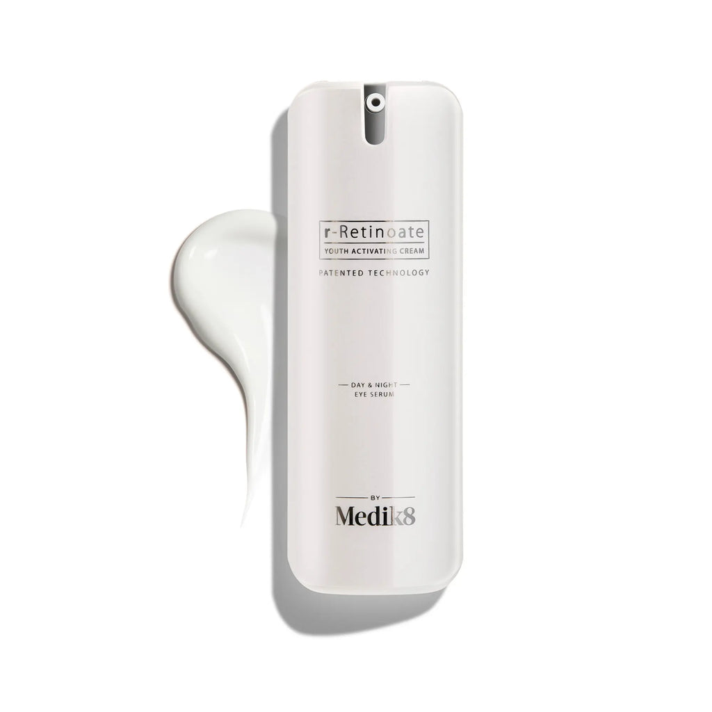 Produktbild av Medik8 r-Retinoate Day & Night Eye Serum, vit flaska med en liten mängd kräm utspridd i bakgrunden.