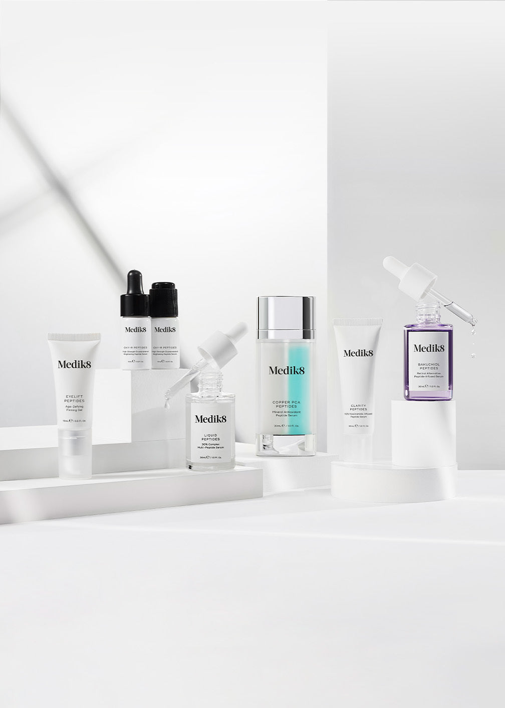 En samling av Medik8:s peptidprodukter på en vit bakgrund, inklusive flaskor och tuber av olika serum.