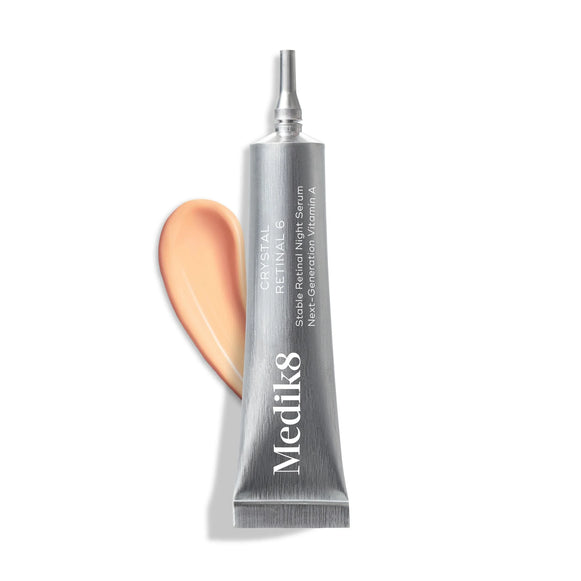 Silverfärgad tub med hudvårdsserum och en aprikosfärgad kräm bredvid, visar Medik8 Crystal Retinal® 6 (Lyxprov) för effektiv retinalskincare.-53
