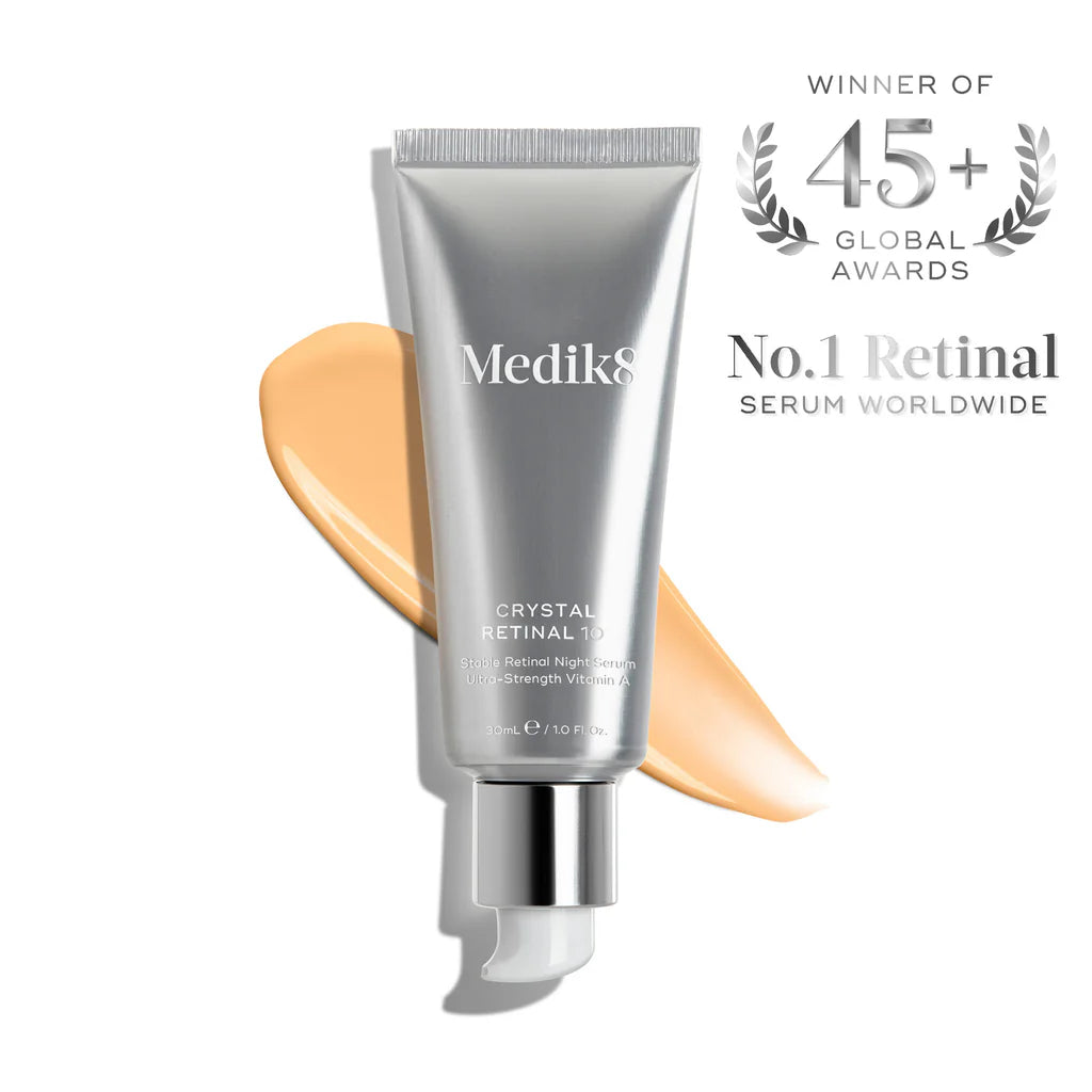 Rörflaska med Medik8 Crystal Retinal hudvårdsserum i silverförpackning med en beige kräm bakom och text som lyfter fram dess globala utmärkelser och effekt som retinolserum.