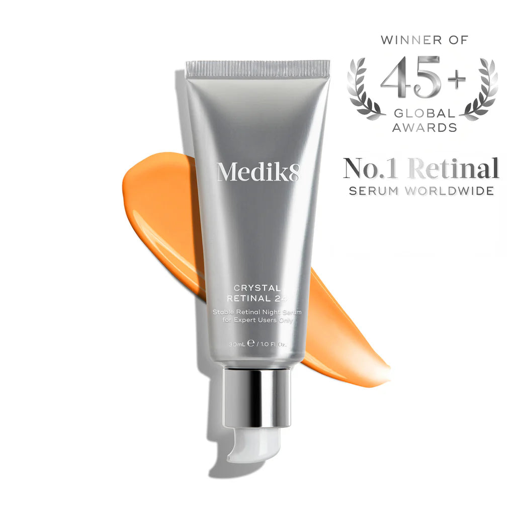 Tube med serum från Medik8 i silverförpackning med orange kräm bakom, Crystal Retinal för avancerad hudvård med retinal som aktiv ingrediens.