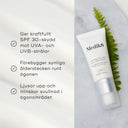 Advanced Day Eye Protect ögonkräm från Medik8 liggande på en ljus yta bredvid ett ormbunksblad, med text om produktens fördelar som solskydd och anti-aging.